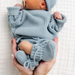 hands holding infant baby feet with knit dusty blue baby booties
