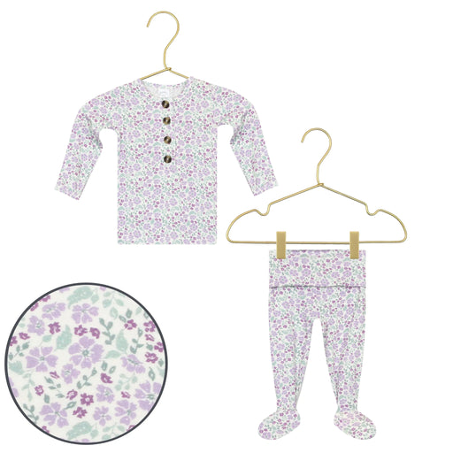 Floral-patterned baby outfit with shirt and pants on hangers against a white background.
