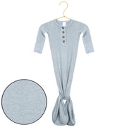 A light heather gray long-sleeve baby tunic with a buttoned henley neckline and a gathered tie at the bottom, shown hanging on a gold hanger with a circular fabric detail inset on the bottom left.