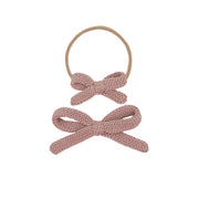 Two pink knitted bows on a white background