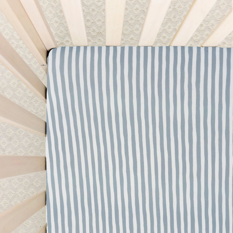 Striped crib sheet with blue and white pattern on a crib