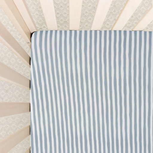 Striped crib sheet with blue and white pattern on a crib