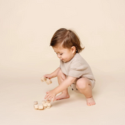 Baby playing with wooden blocks on a beige background