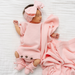 Newborn baby wrapped in a pink blanket and wearing a matching headband on a white background