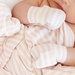 baby wearing pink and white striped mittens
