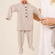 Lou Lou & Co Banks newborn striped top and bottom set in beige and white being held on hanger by adult in neutral outfit