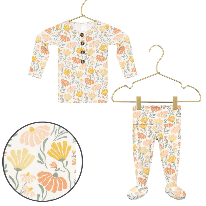 Lou Lou & Co Phoebe newborn top and bottom set in cream with orange, yellow, and peach floral print displayed on gold hangers