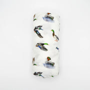 Flatlay of Saltwater Swaddles Lucky Ducks bamboo and cotton swaddle blanket showing multiple colorful duck illustrations