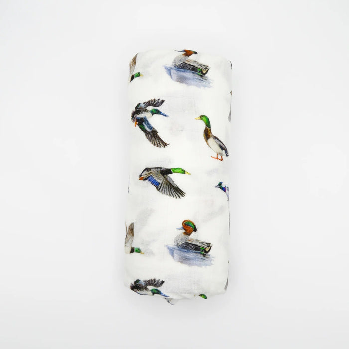 Flatlay of Saltwater Swaddles Lucky Ducks bamboo and cotton swaddle blanket showing multiple colorful duck illustrations