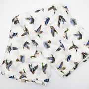 Flatlay of Saltwater Swaddles Lucky Ducks bamboo and cotton swaddle blanket showing multiple colorful duck illustrations