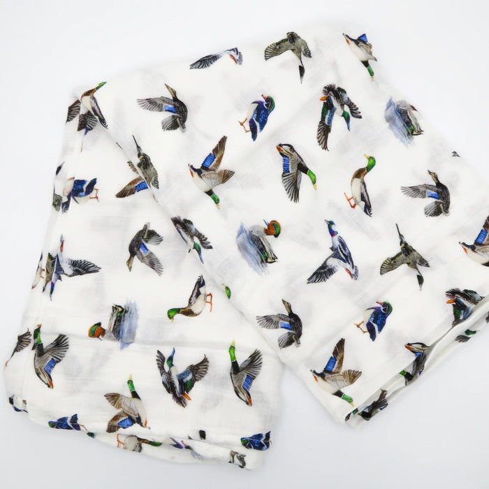 Flatlay of Saltwater Swaddles Lucky Ducks bamboo and cotton swaddle blanket showing multiple colorful duck illustrations