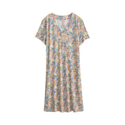 A short-sleeve V-neck dress with an all-over dense floral print in muted blue, beige, orange, and yellow tones, shown flat against a light off-white background.