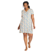 A woman modeling a short-sleeve V-neck nightgown with a light blue, yellow, and white floral pattern, standing against a plain light gray studio background.