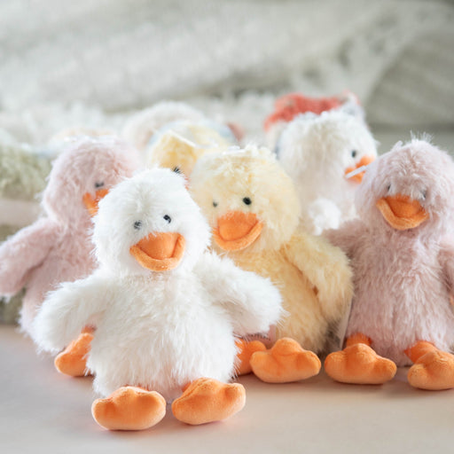 Set of plush ducks in various colors on a light surface with a textured blanket in the background.