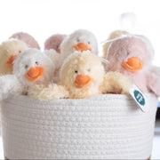 White woven basket with plush toy ducks on a light background