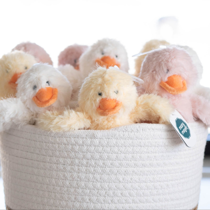 White woven basket with plush toy ducks on a light background