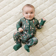 baby wearing green nutcracker bamboo coverall lying on quilted blanket