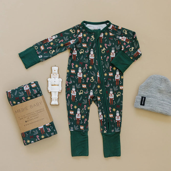 flat lay of green nutcracker bamboo coverall with matching accessories toy and beanie