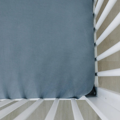 Close-up of the Mebie Baby Bamboo Crib Sheet in Dusty Blue fitted snugly around a crib mattress corner