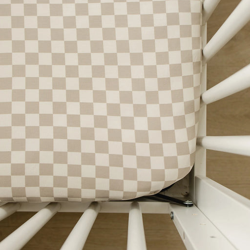 closeup of taupe checkered bamboo crib sheet on mattress corner