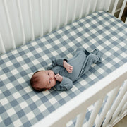 Newborn sleeping in a white crib with the Mebie Baby Dusty Blue Gingham Muslin Crib Sheet