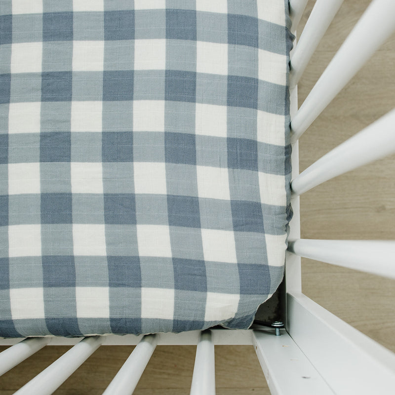 Mebie Baby Muslin Crib Sheet in Dusty Blue Gingham fitted on a mattress in a white crib