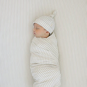 newborn swaddled on taupe stripe ribbed bamboo crib sheet top view