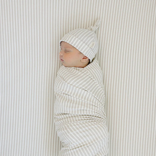 newborn swaddled on taupe stripe ribbed bamboo crib sheet top view