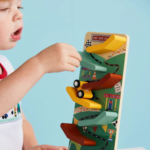 toddler playing with mud pie race car ramp dropping cars down tracks