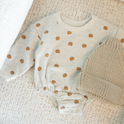 Baby onesie with pumpkin pattern on a textured surface