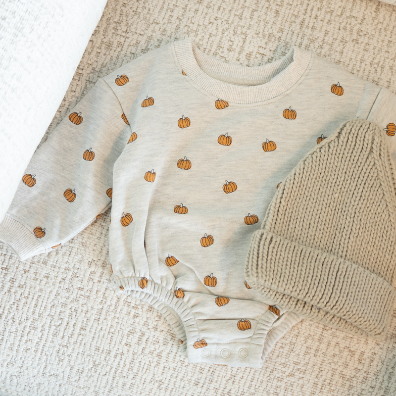 Baby onesie with pumpkin pattern on a textured surface