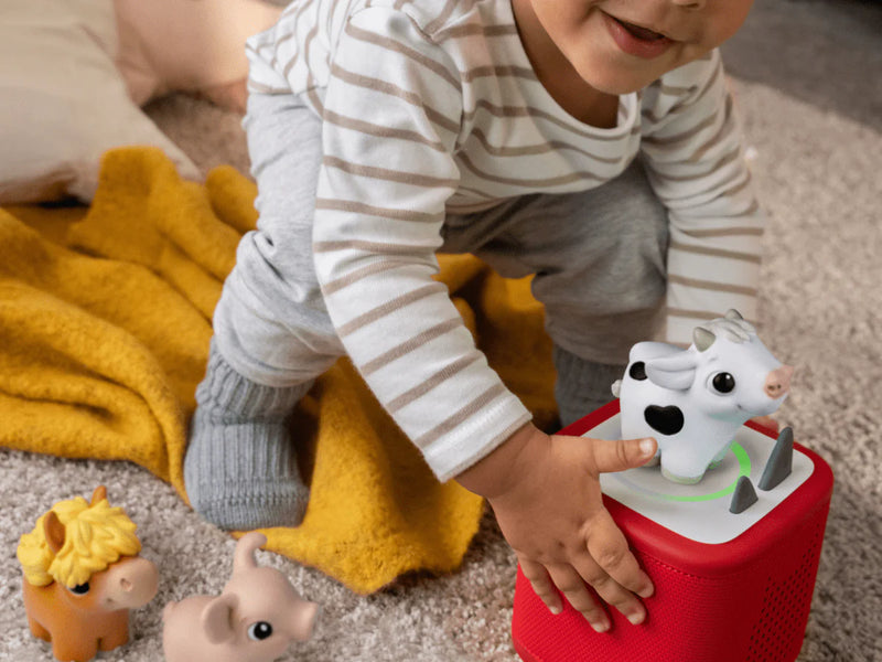 Toddler playing with My First Tonies Farm Set figures and a Toniebox in a playroom