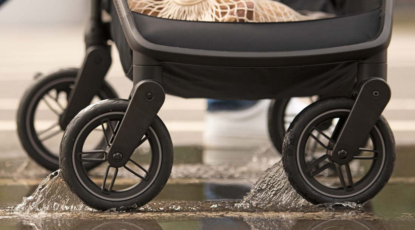 Close-up of a baby stroller with wheels on a wet surface