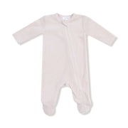 A soft oatmilk-colored velour footie with a diagonal zipper and built-in feet.