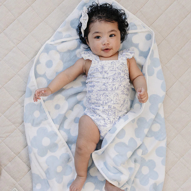 Baby wrapped in a floral blanket on a quilted surface