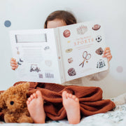 Child reading a book with a teddy bear on a bed