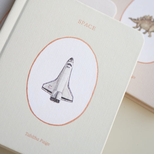 board book with space shuttle illustration on a beige background