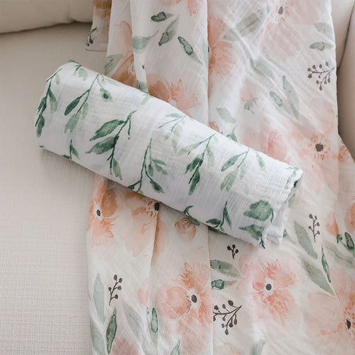 Rolled Parker swaddle resting on matching floral muslin fabric