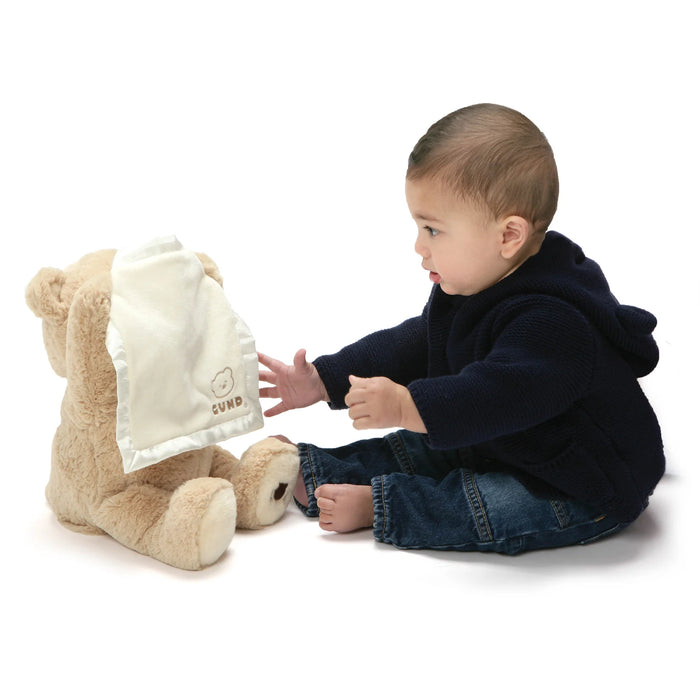 Baby playing peek-a-boo with GUND Animated Bear and satin blanket on white background