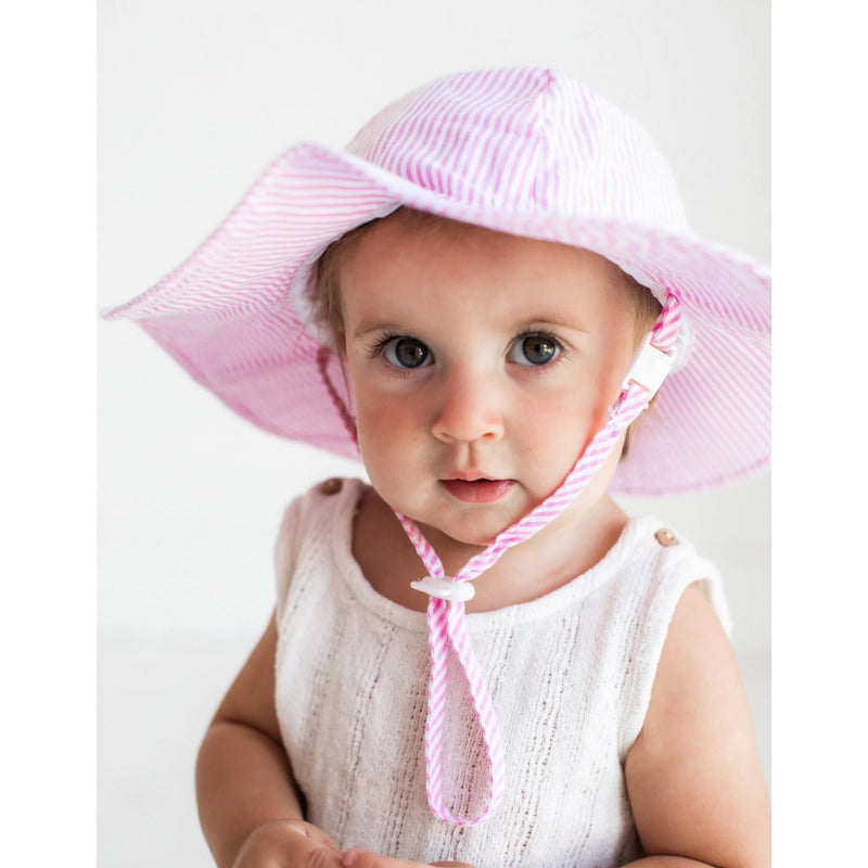 Baby wearing a pink sun hat on a white background