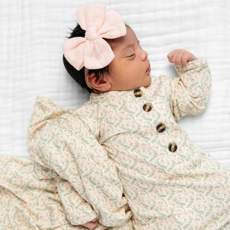 Newborn baby wearing a floral outfit and pink headband on a white background