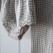 Close-up of a checkered garment with lace eyelet  trim on a white background