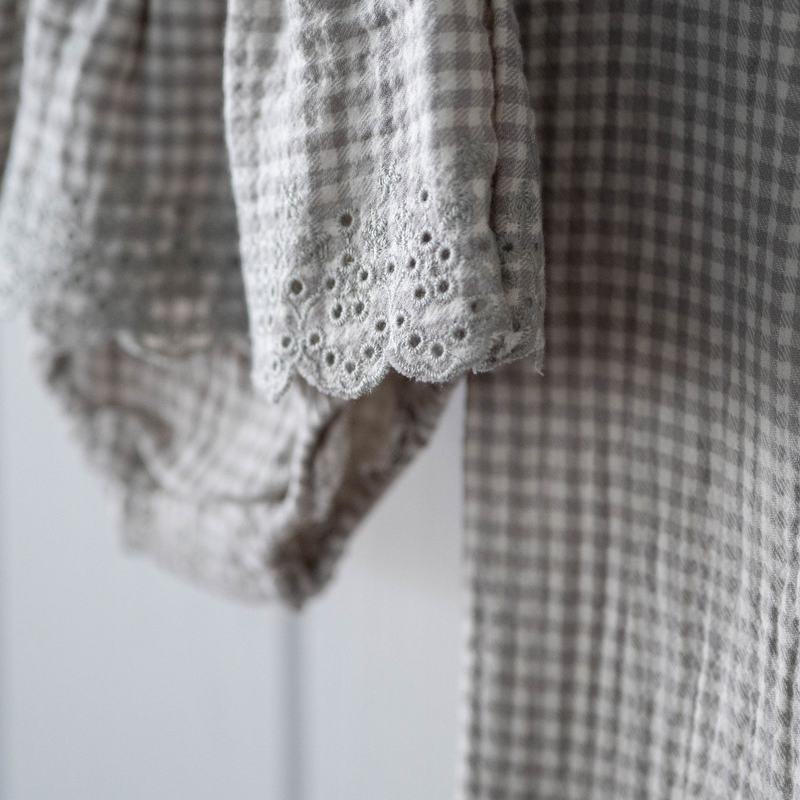 Close-up of a checkered garment with lace eyelet  trim on a white background