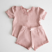 Pink children's outfit with top and shorts on a light gray background