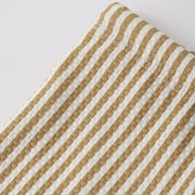 Close-up of a fabric with brown and white striped pattern on a light gray background