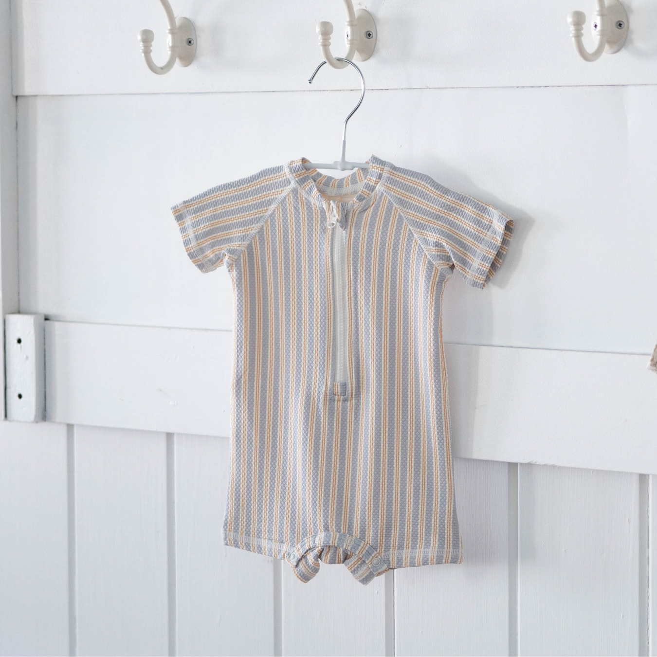 toddler boy wearing blue long sleeve rash guard swimsuit holding a blue ball