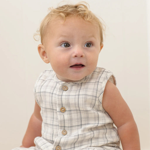 Baby wearing a checkered outfit with a plain background