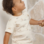 Child wearing a white shirt with small prints against a neutral background