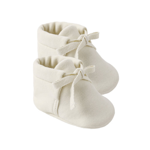 Pair of white baby booties with bow details on a white background