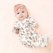 Baby girl wearing the cowgirl footie on a blush blanket.